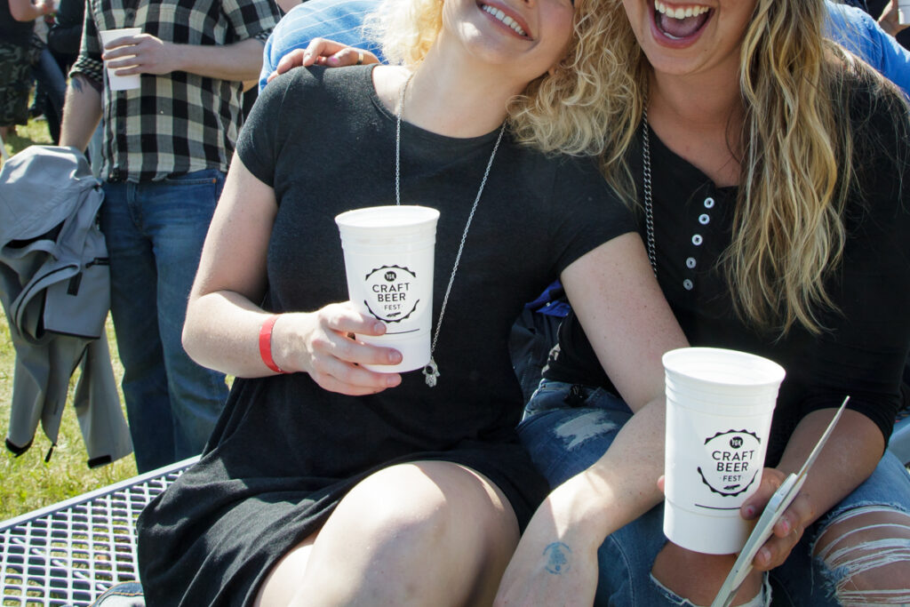 Two girls in black dressing holding white branded cups