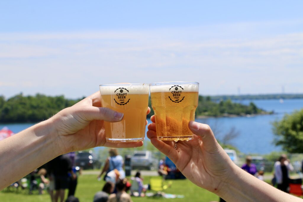 Two beer filled glasses being held in the air.